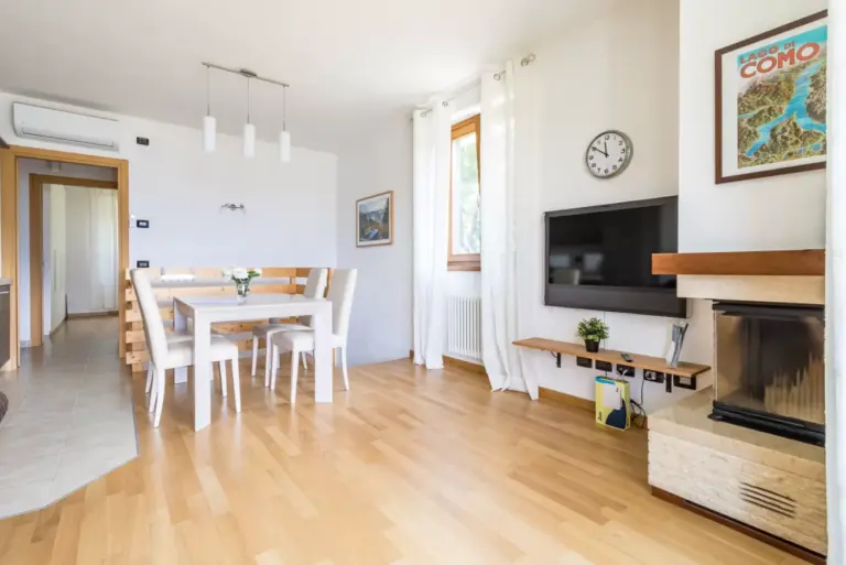 Open space soggiorno e pranzo dell'Appartamento Gli Ulivi 4 con camino, tavolo bianco e aria condizionata