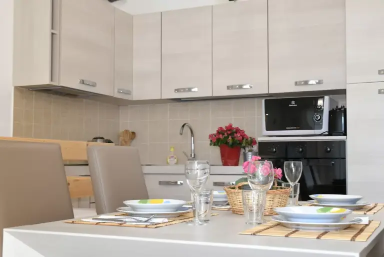 Cucina attrezzata e tavolo da pranzo apparecchiato dell'Appartamento Gli Ulivi 10 a Tremezzina