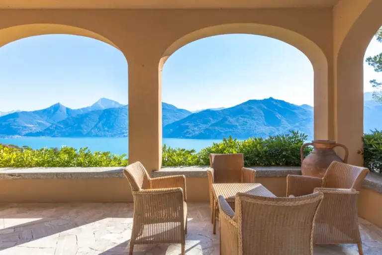 Loggia panoramica di Villa Gaia a Menaggio con poltrone in vimini e vista sul Lago di Como