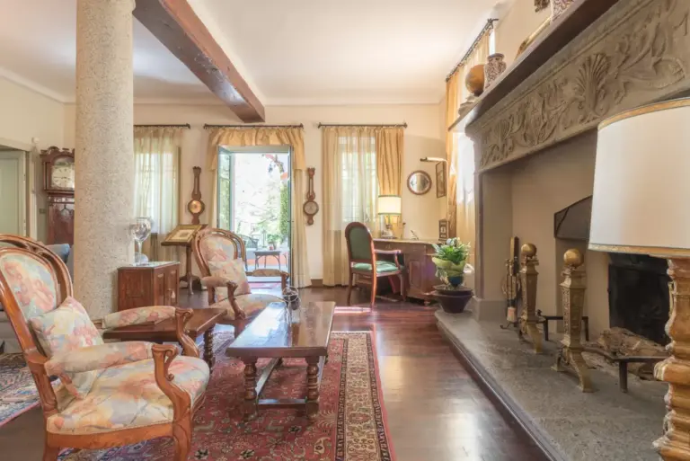 Salotto d'epoca di Villa Rondinella a Tremezzina con grande camino in pietra scolpita e poltrone d'antiquariato