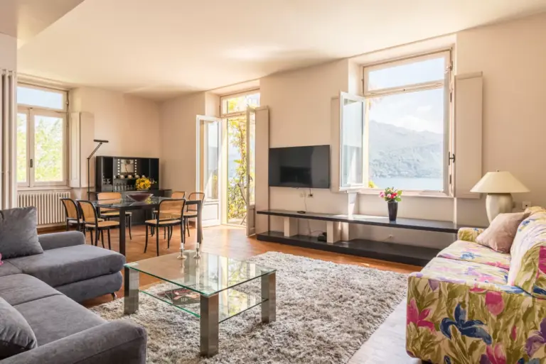 Ampio soggiorno luminoso di Apartment Yoko con divani, tavolo da pranzo e finestre con vista sul Lago di Como
