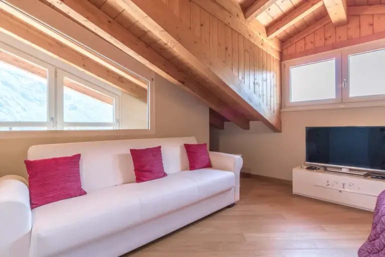 Salotto mansardato di Tulipani 13 con divano-letto, soffitti in legno e finestra sulle montagne del Lago di Como
