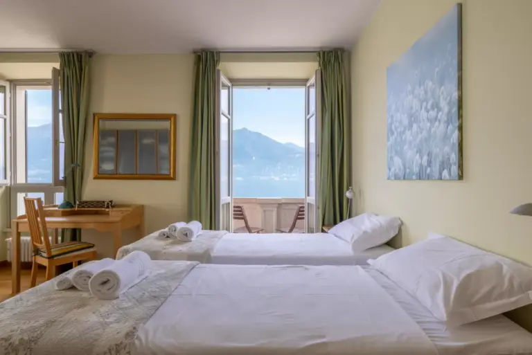 Camera da letto dell'Appartamento Julia con due letti singoli, scrivania e finestre affacciate sul Lago di Como