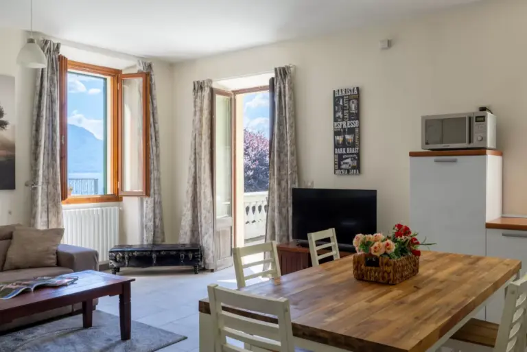 Zona giorno con tavolo da pranzo e finestra con vista lago all'Appartamento Katia a Menaggio