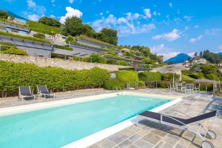 Piscina condivisa del residence di Apartment Maria con lettini e vista sul Lago di Como