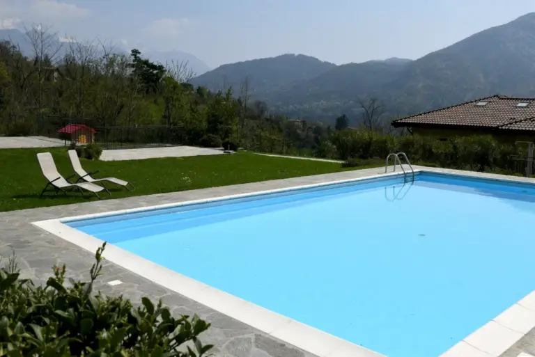 Piscina condivisa del Residence Gli Ulivi con lettini e panorama sulle montagne di Tremezzina
